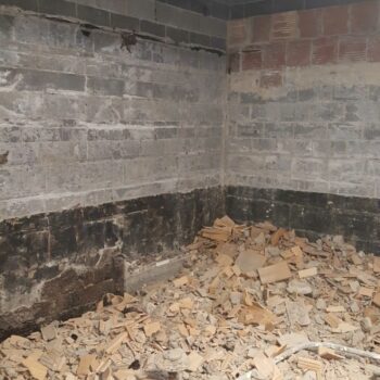 A demolished room with exposed brick and piles of bricks and stone on the ground