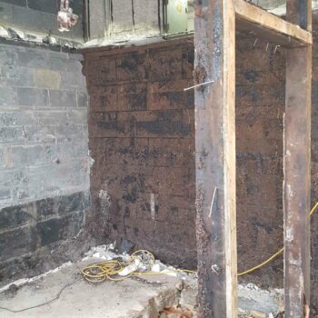 A construction site with exposed brick and wires on the cement floor
